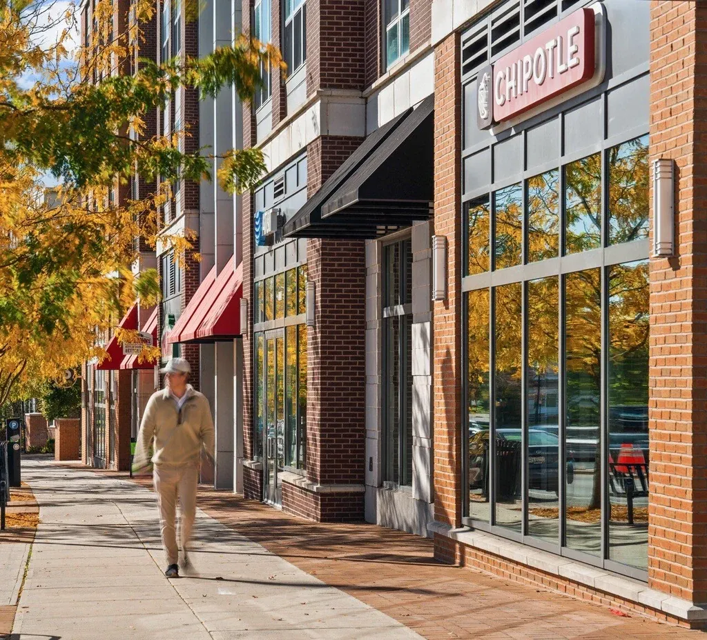 Brick retail storefront on a tree-lined shopping street in autumn — retail streetscape photography by Umedia