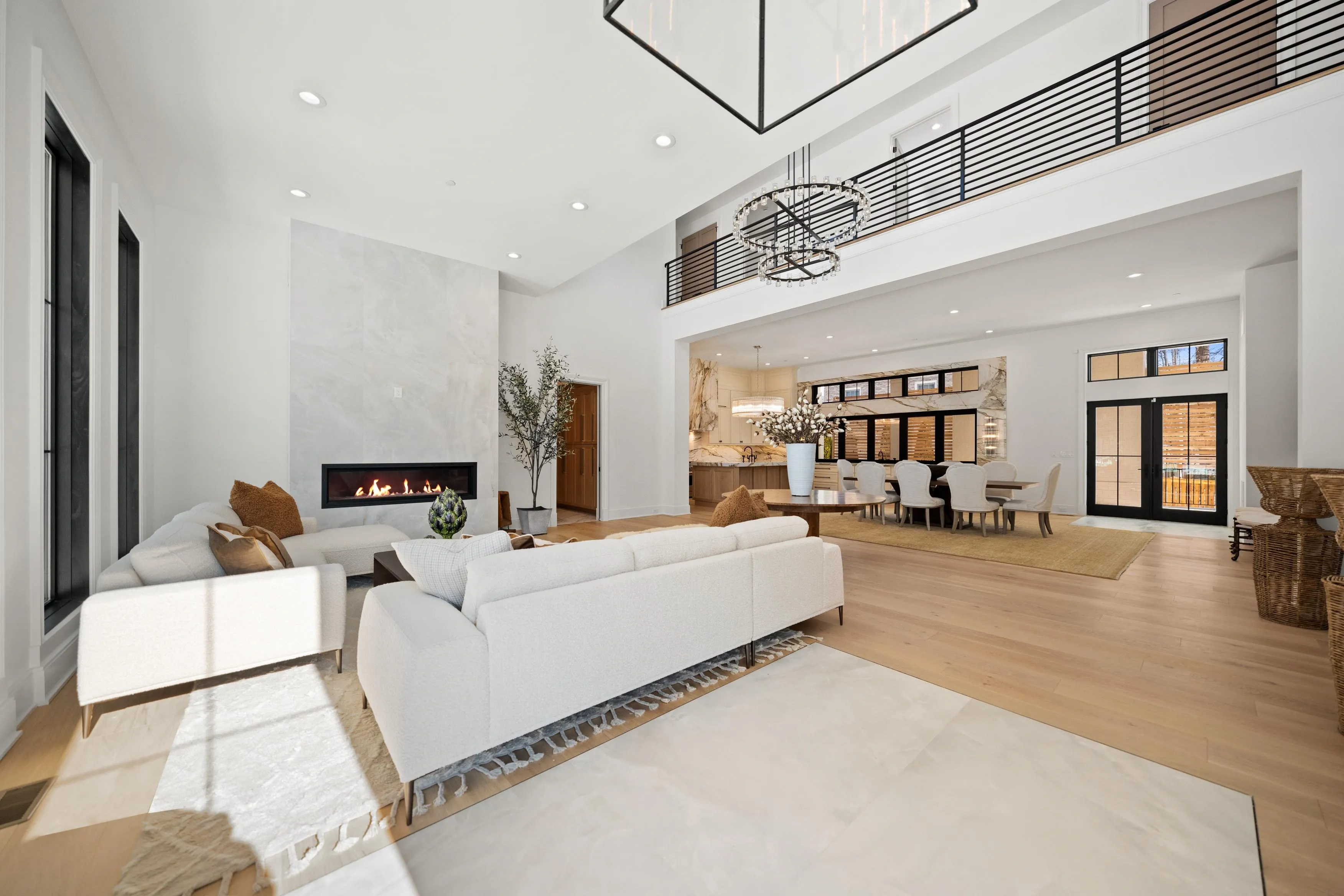 Open-concept great room with linear fireplace, double-height ceiling, and iron railing overlook in Bethesda luxury home