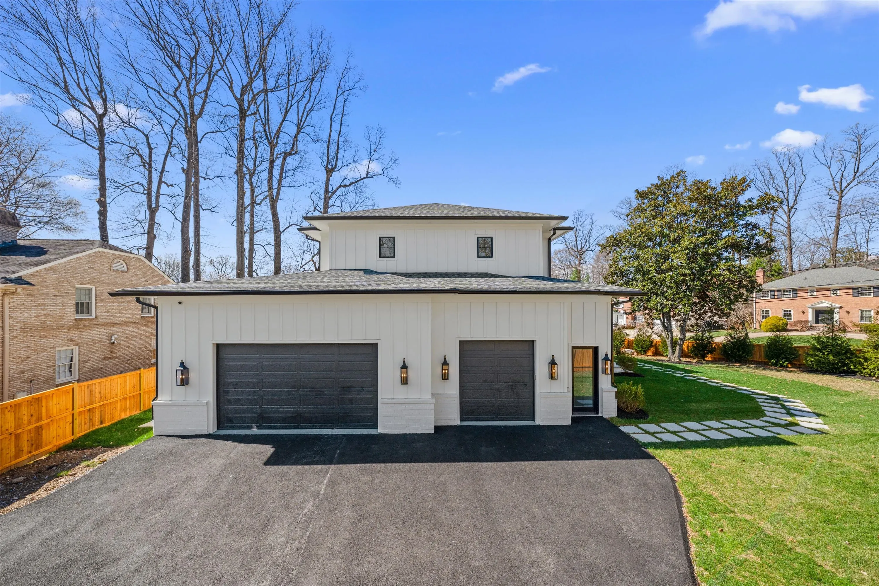 Detached two-bay carriage-style garage with stone accents and board-and-batten siding at luxury new construction in Bethesda, Maryland