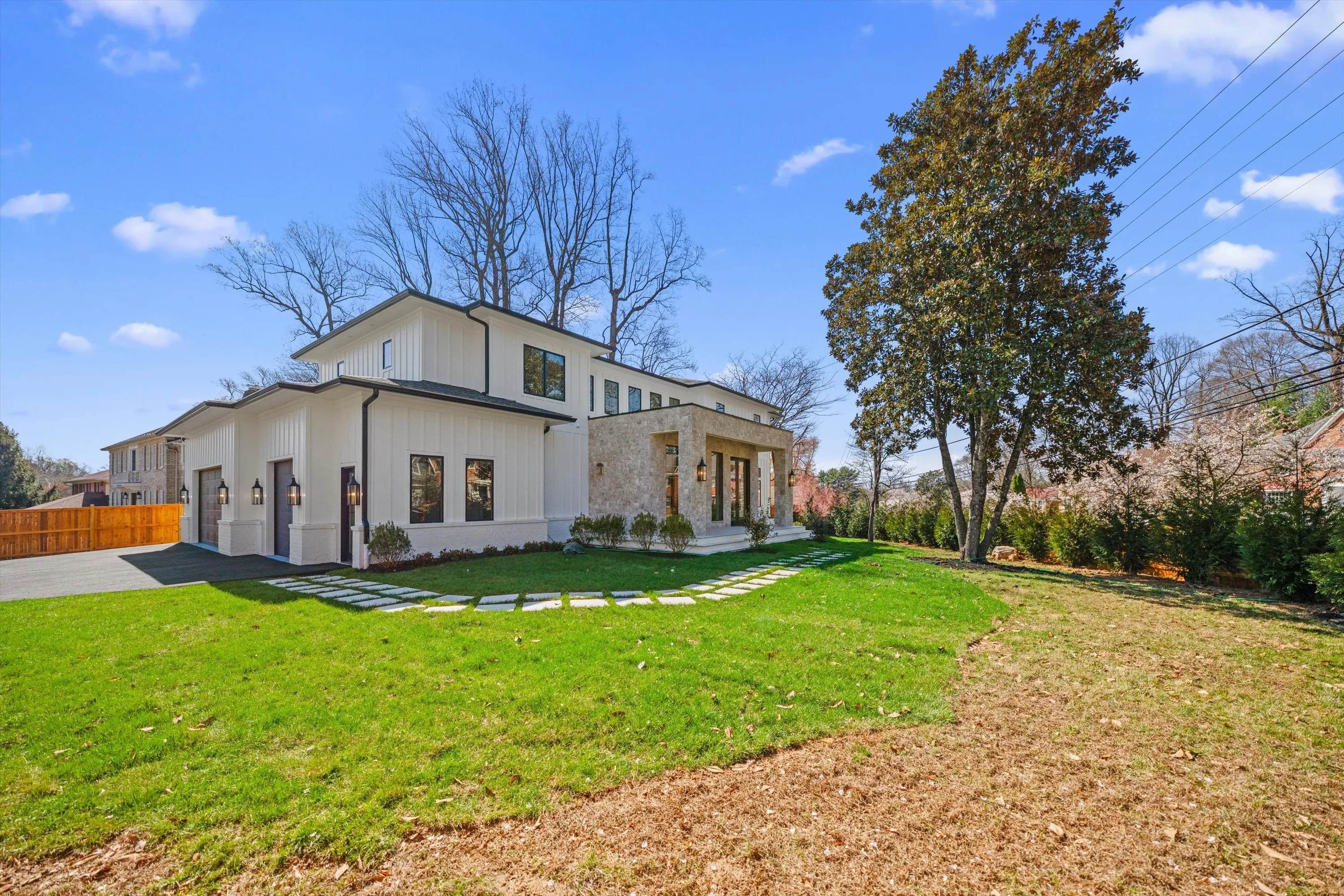 Wide front view of luxury Bethesda new construction showing main house, detached garage, and stepping-stone walkway