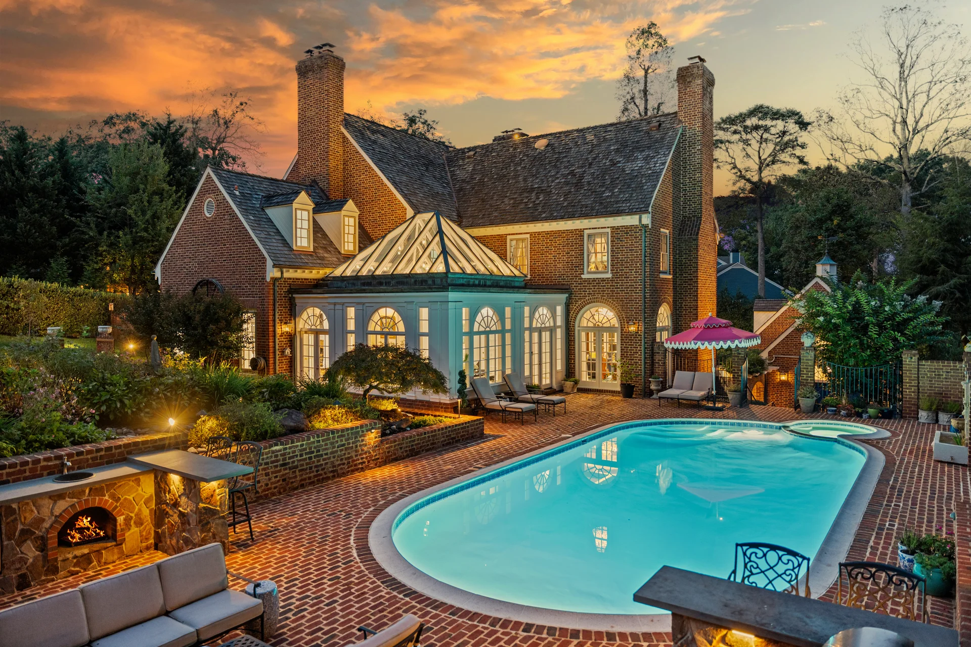 Twilight real estate photography of a luxury brick colonial home with pool, brick patio, and outdoor fireplace in McLean Virginia by Umedia