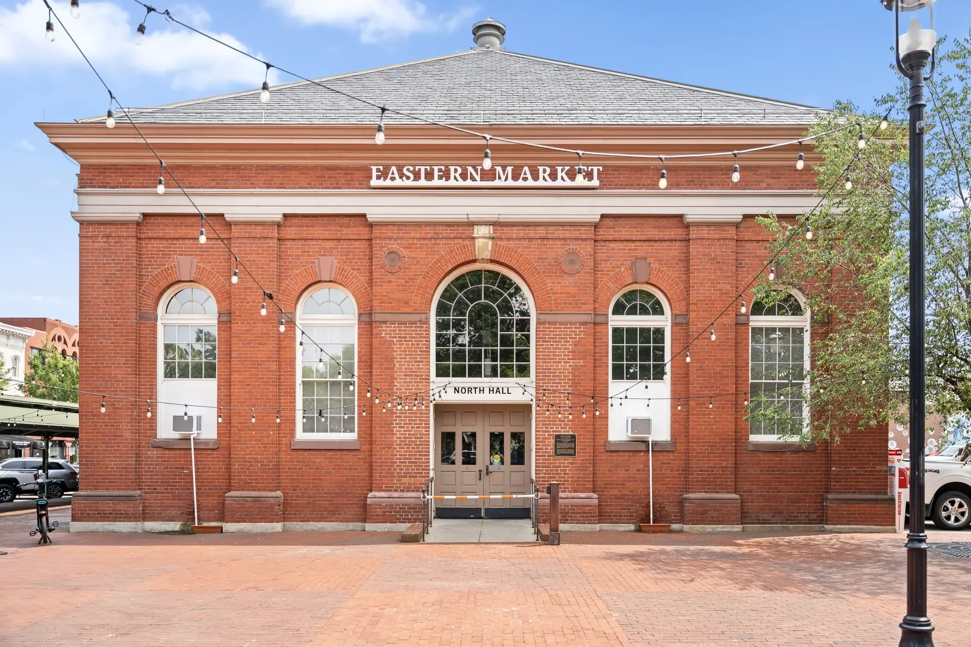 Eastern Market red-brick North Hall facade with plaza and string lights, Capitol Hill, Washington, DC