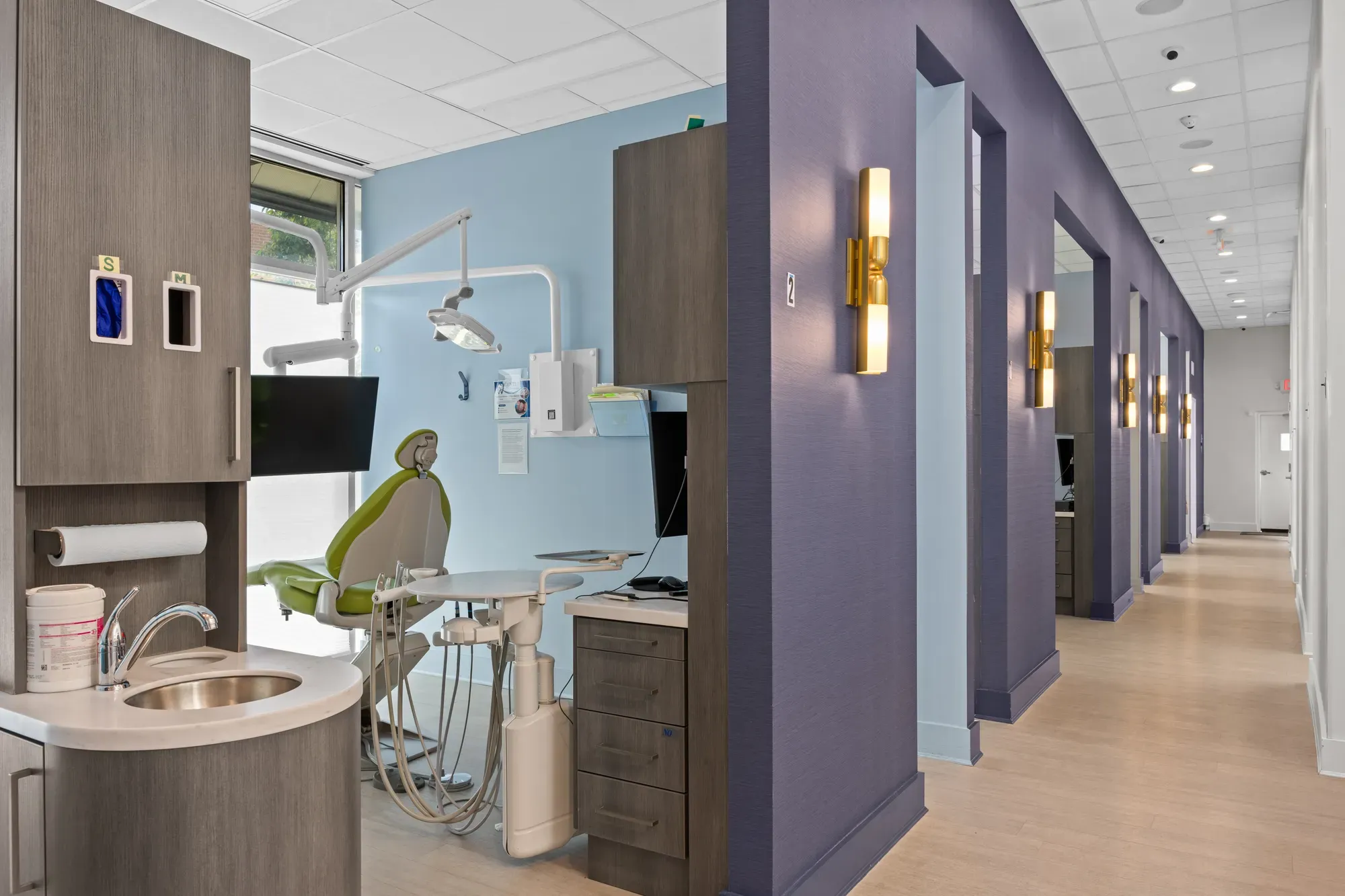 Dental clinic operatory corridor with treatment rooms and modern dental chair — medical office photography by Umedia