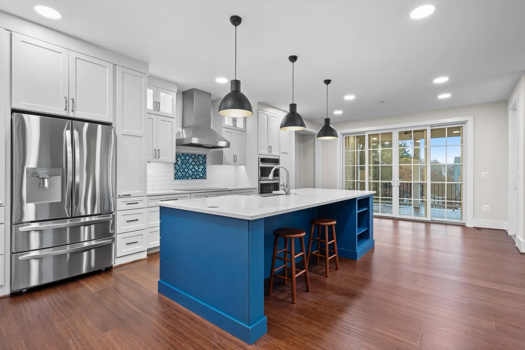 Gourmet kitchen with navy blue island, white shaker cabinets, and pendant lights