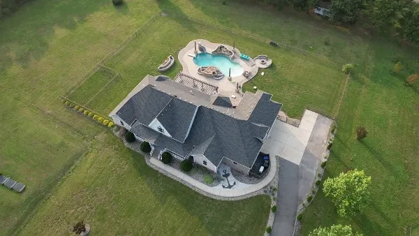 FAA-licensed aerial drone photography of a luxury waterfront mansion with private dock, expansive lawn, and bay views by Umedia