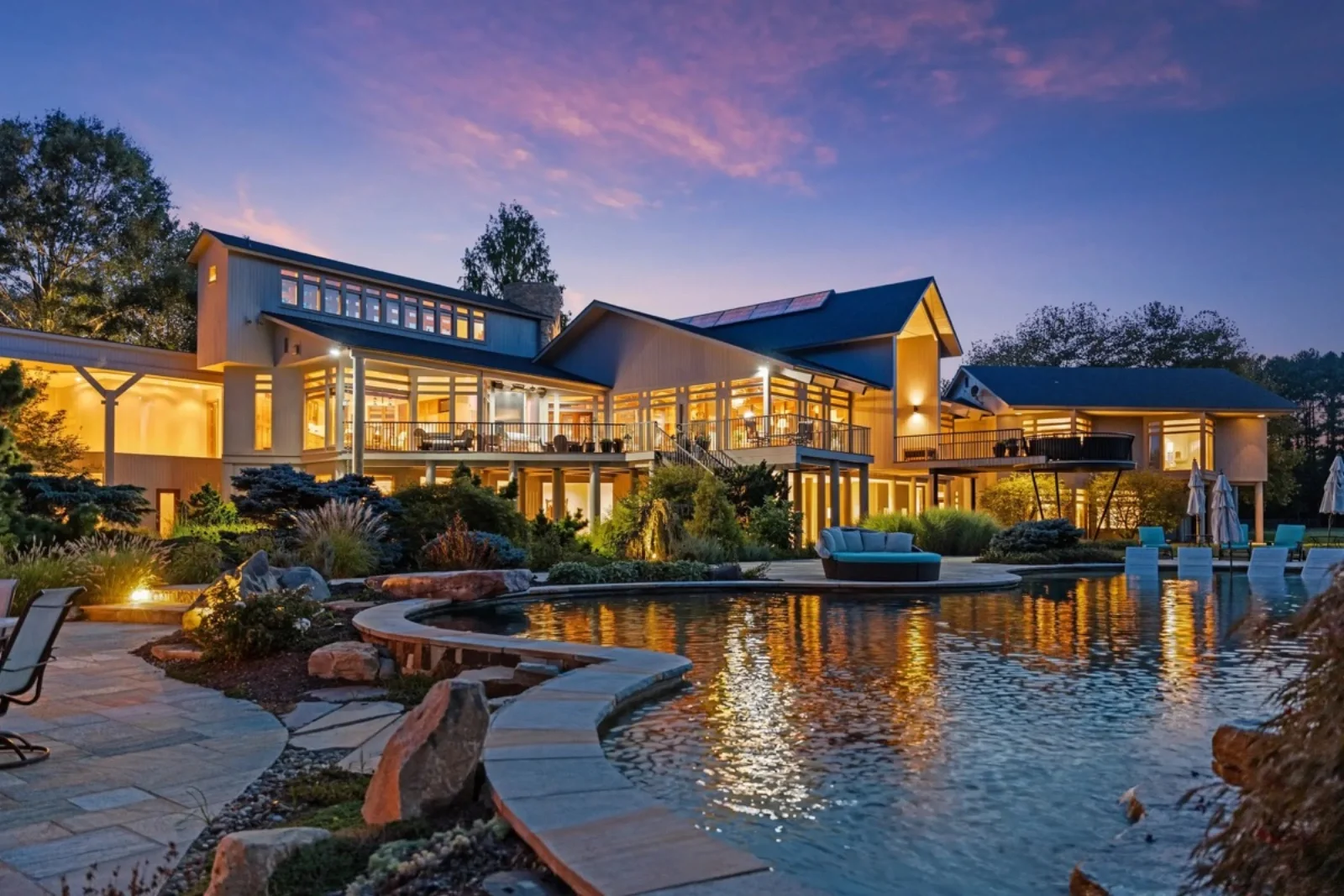 Twilight photography of a luxury waterfront vacation rental with reflecting pool and illuminated interior — Airbnb and VRBO rental photography by Umedia