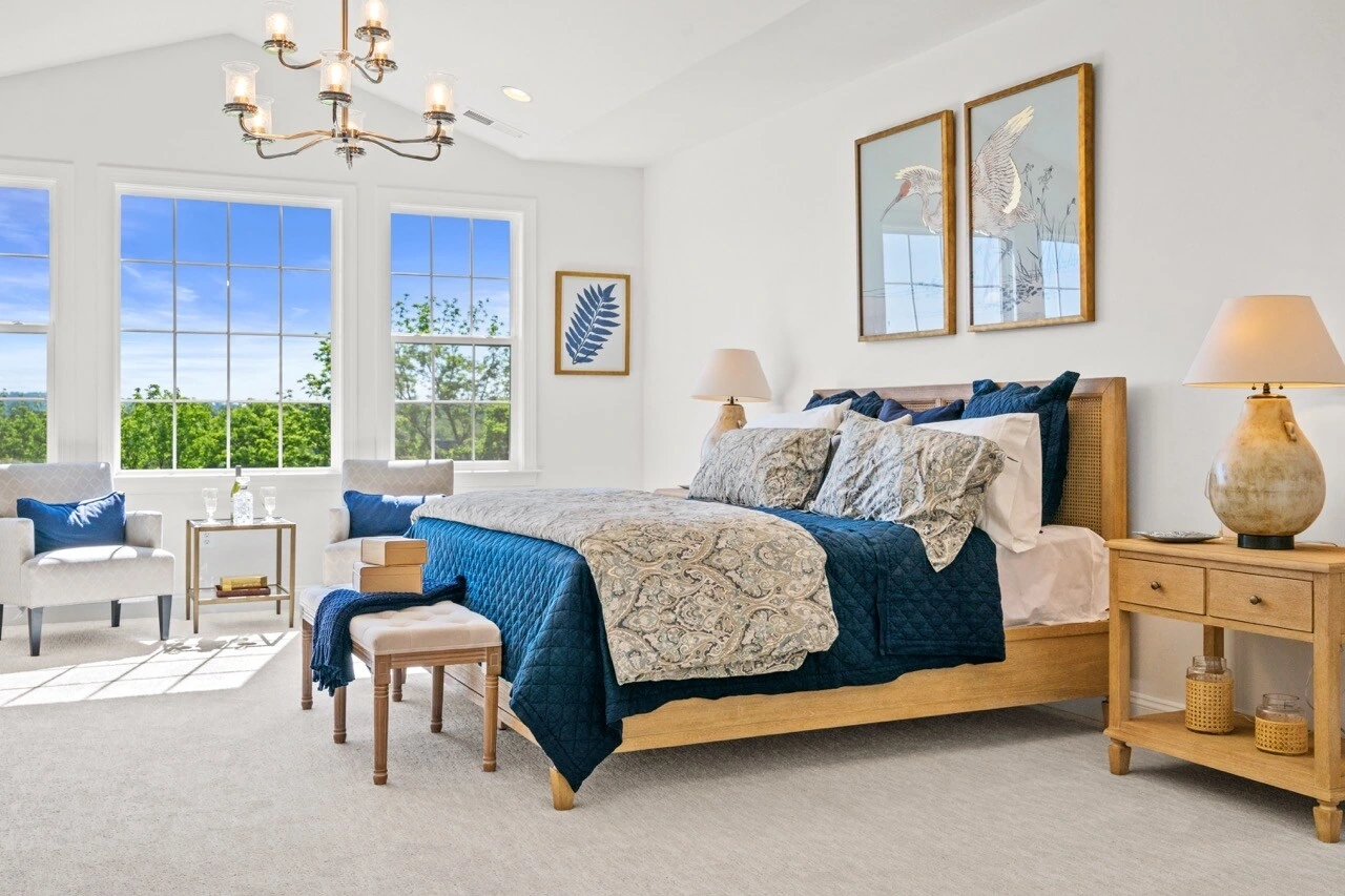 Furnished primary bedroom with vaulted ceiling and natural light