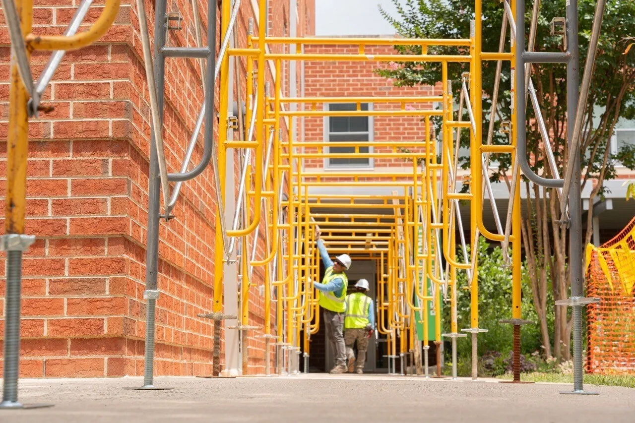 Workers on a scaffolded walkway during brick building renovation — construction site photography by Umedia