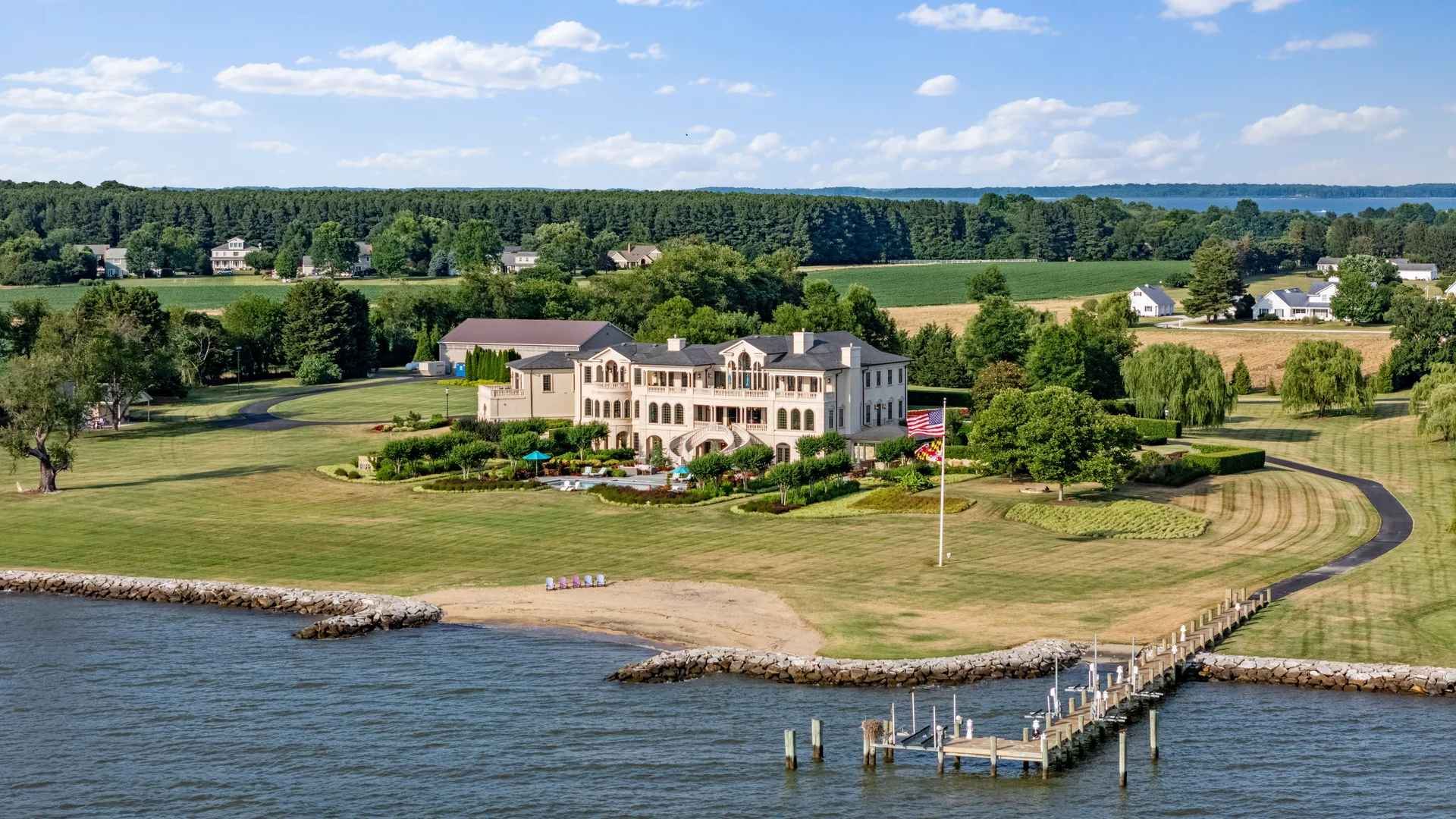 FAA-licensed aerial drone photography of a luxury waterfront mansion with private dock, expansive lawn, and bay views by Umedia