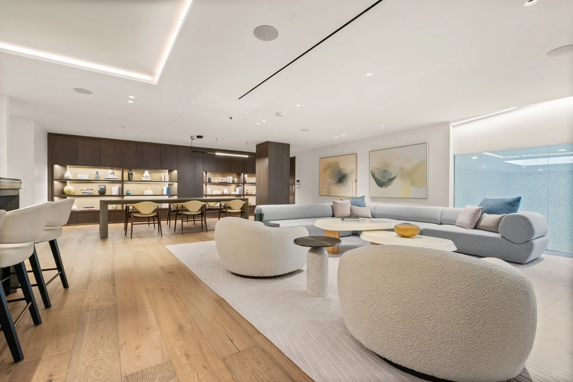Interior real estate photography of a modern open-concept living room and kitchen with curved sofas and wide-plank wood flooring in Bethesda Maryland by Umedia