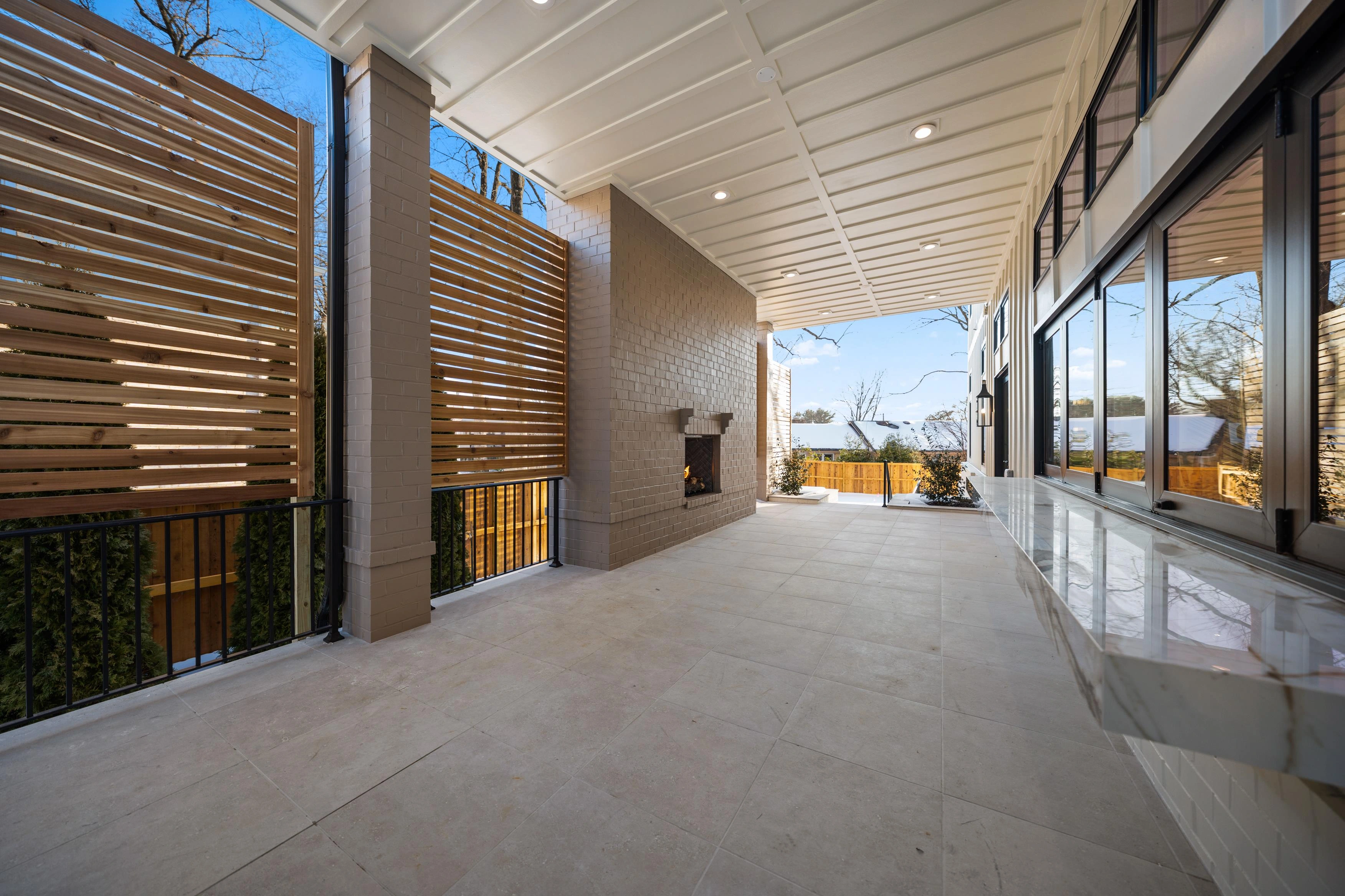 Covered patio with outdoor fireplace, cedar privacy screens, marble bar counter, and tongue-and-groove ceiling