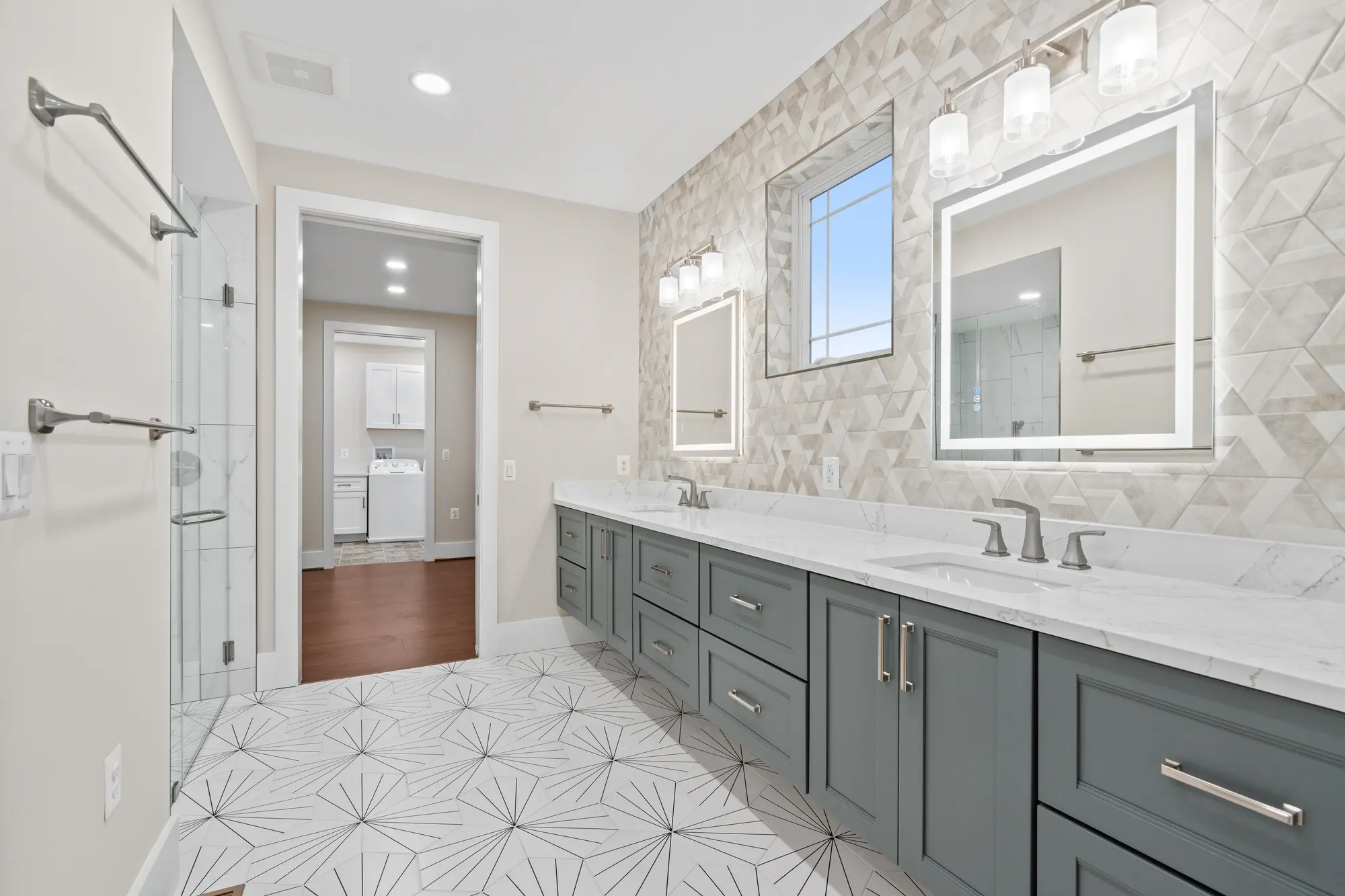 Modern bathroom with dual vanity, mosaic floor tile, and soaking tub