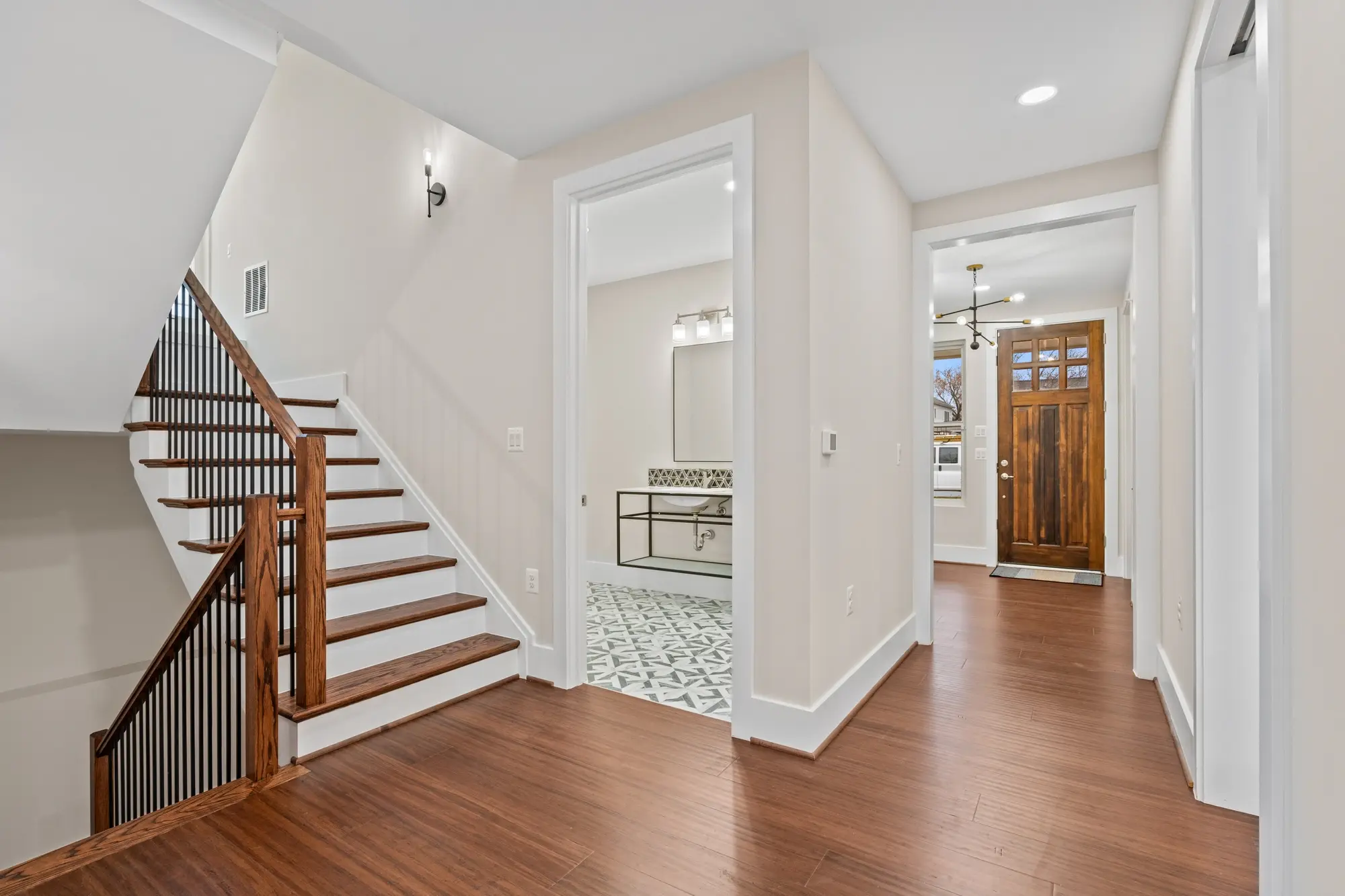 Open foyer with modern staircase, iron balusters, hardwood floors, and powder room