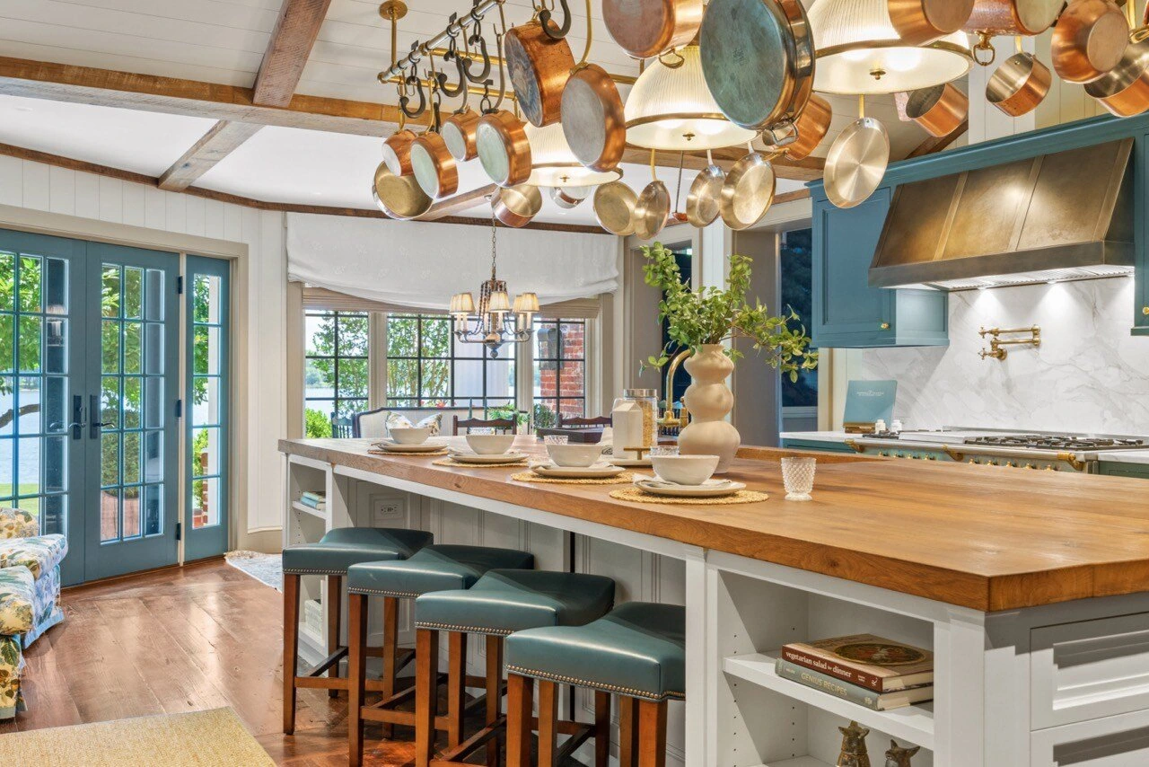 Gourmet farmhouse kitchen with butcher-block island, copper pot rack, and blue cabinets
