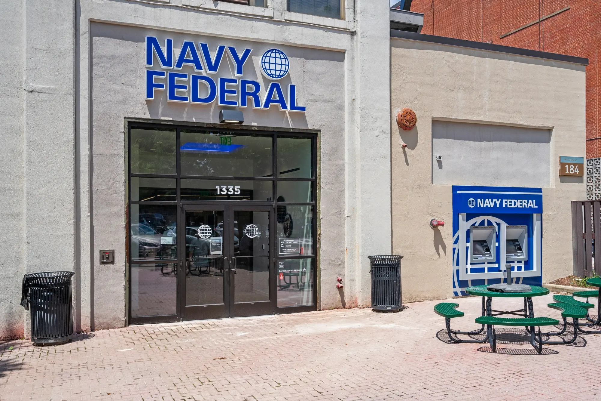 Navy Federal Credit Union entrance facade close-up with illuminated globe logo, address 1335, and glass double doors