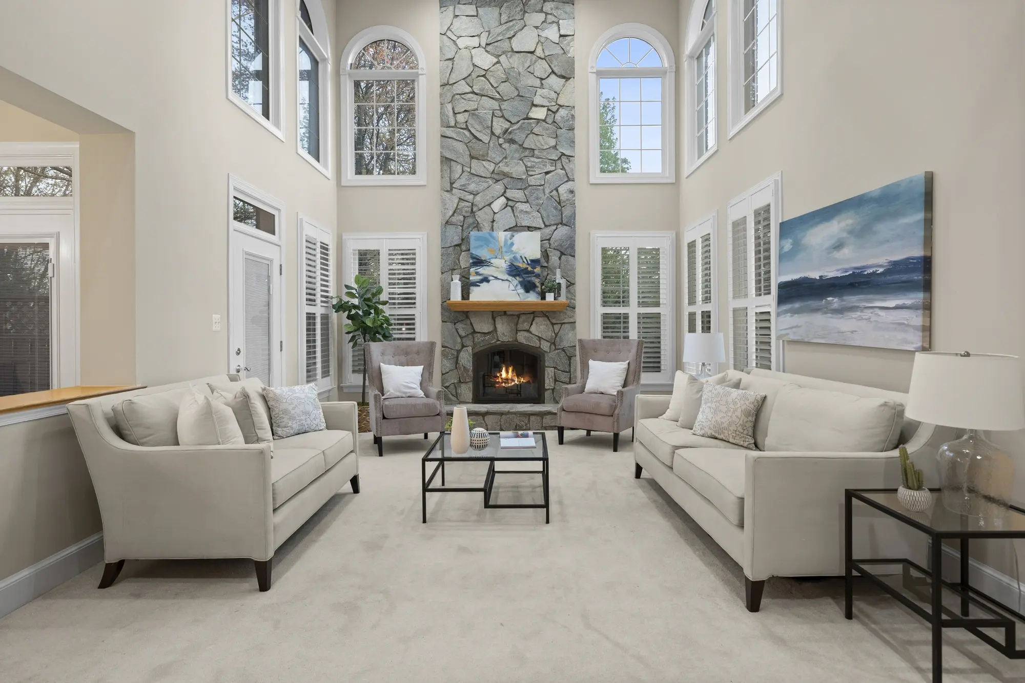 Grand living room with stone fireplace and furnished seating