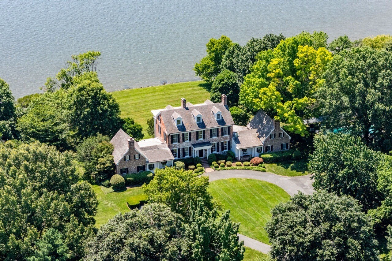 Aerial drone photography of waterfront colonial estate with manicured grounds and private dock