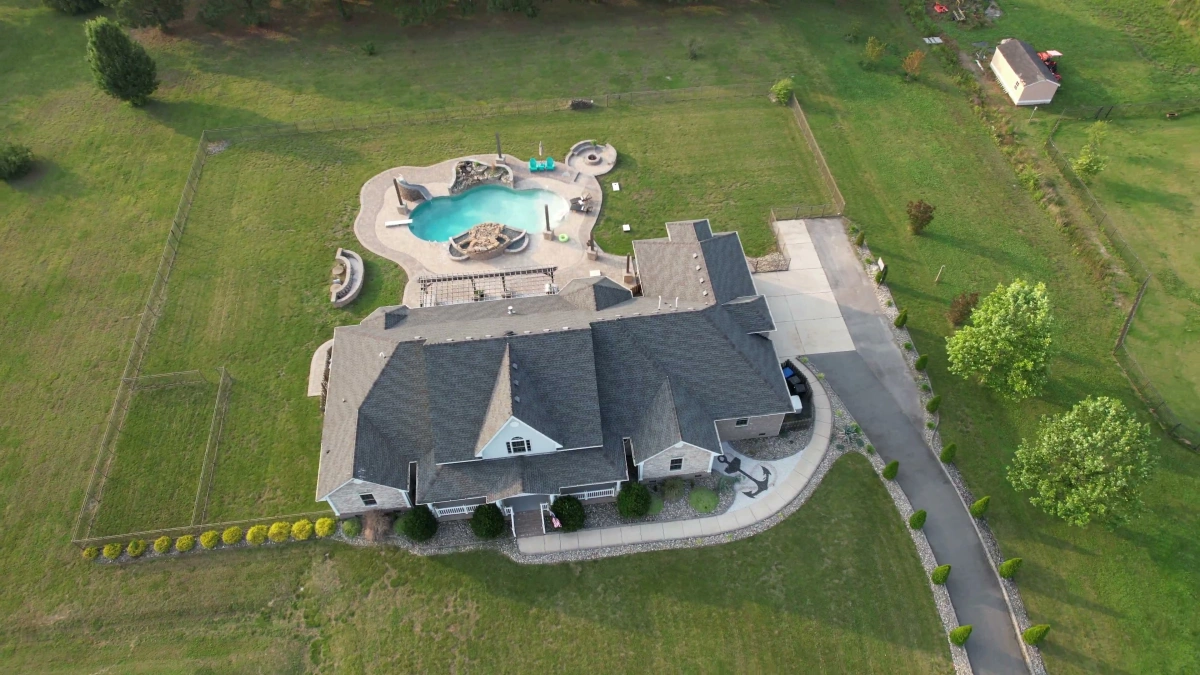 Aerial drone view of luxury estate with pool and landscaping