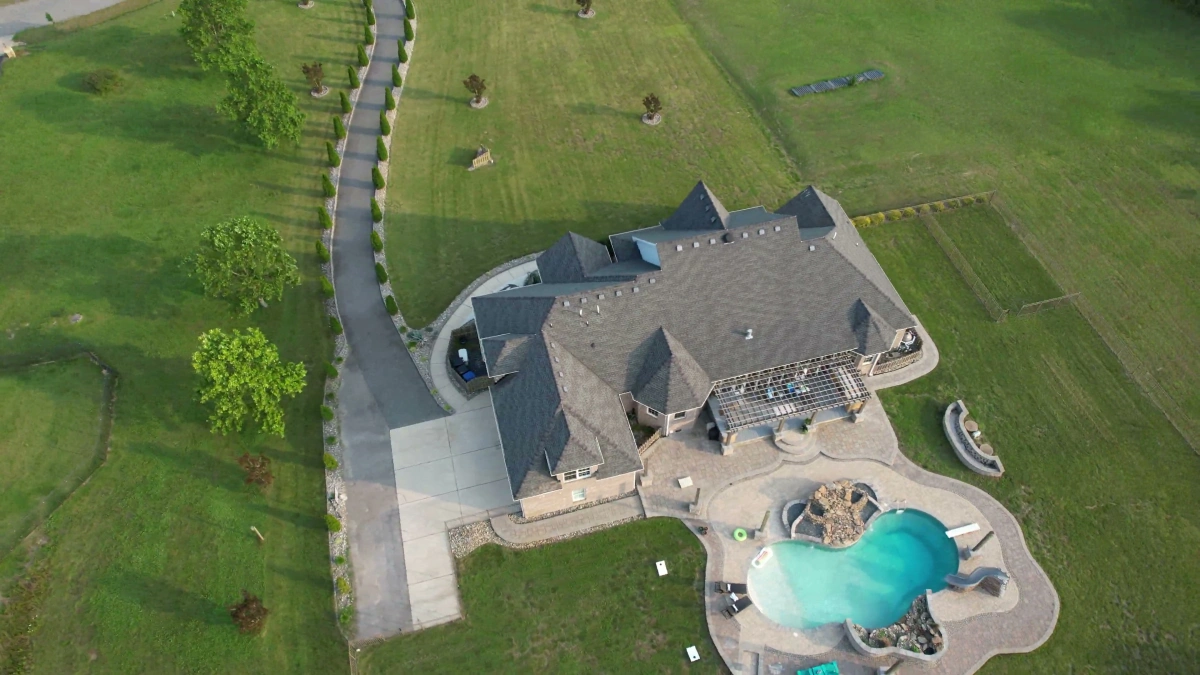 Wide overhead drone view of property with custom pool